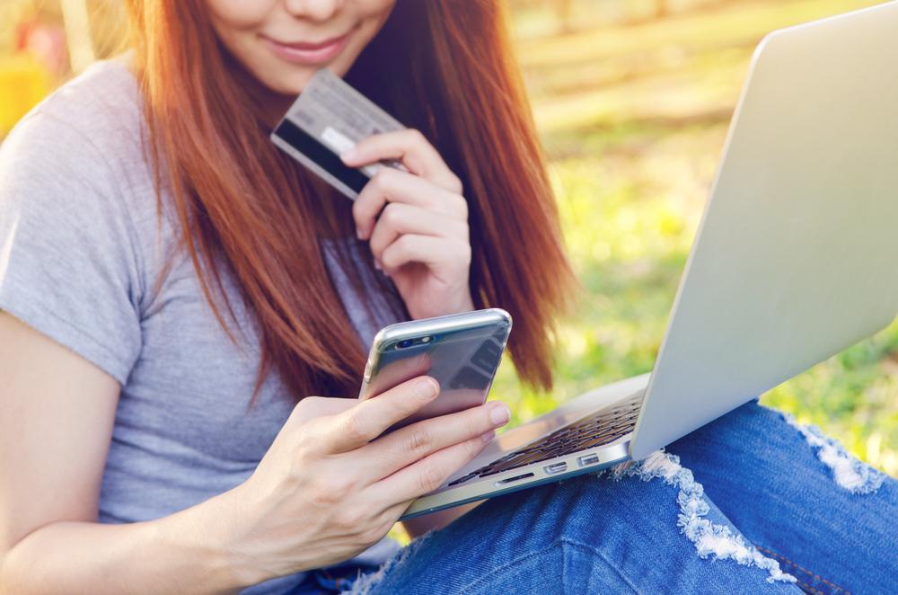 young woman using her credit card in front of her laptop