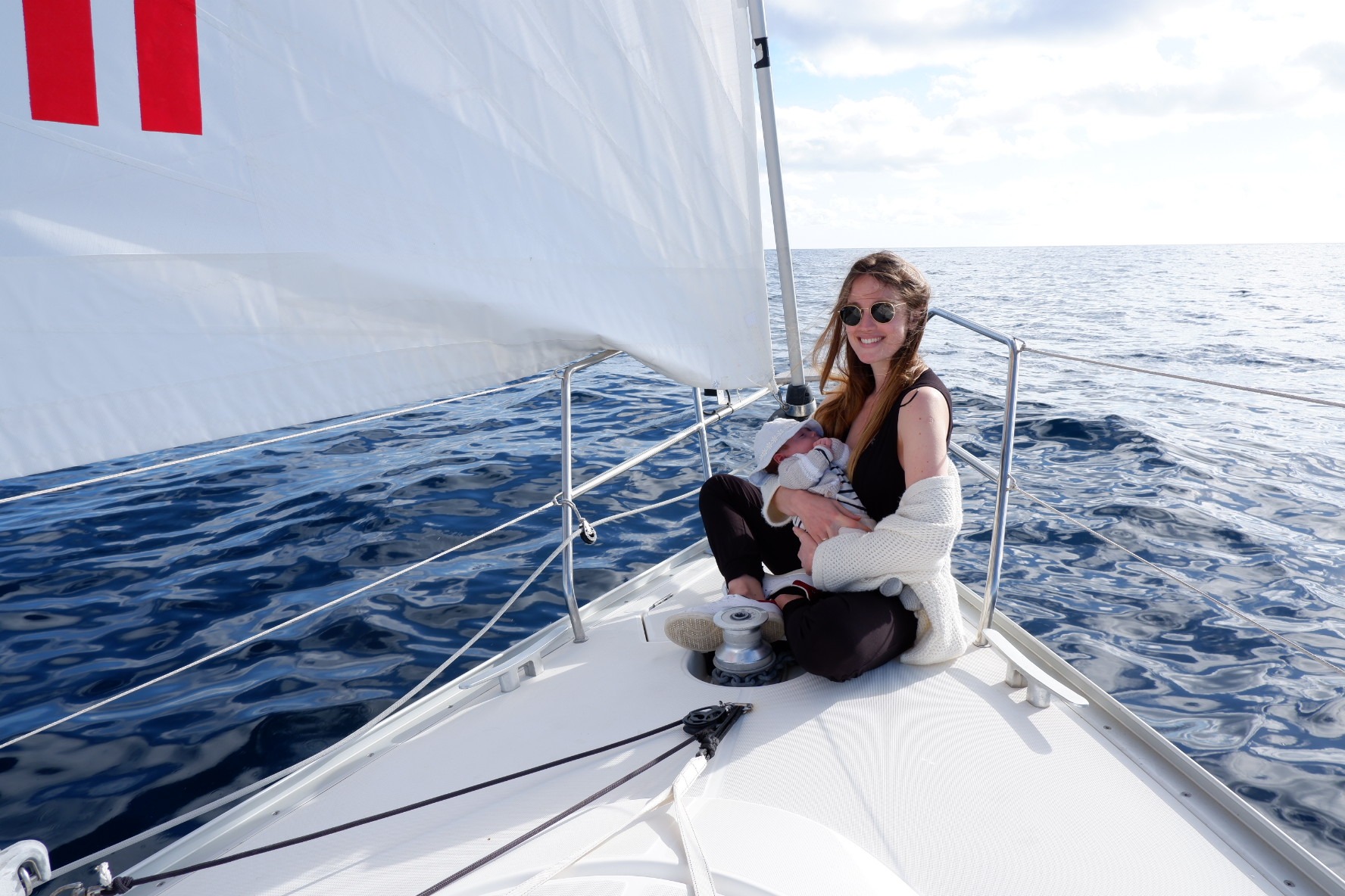 Sofia de Dorlodot on the sailboat with her baby in her arms