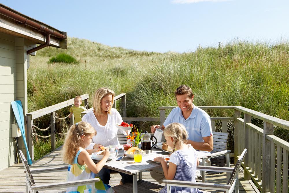 Family on holiday in a house near the dunes, having breakfast